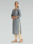 Woman wearing a gray floral patterned kurta with beige pants on a light gray background