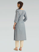 “A woman dressed in a gray patterned kurta paired with beige pants, captured in a graceful back pose on a light gray background.”