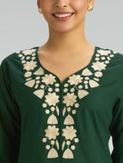 Green traditional outfit with white floral embroidery on a neutral background