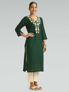 Woman wearing a green kurta with floral embroidery on a gray background