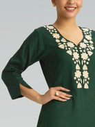 Green dress with white floral embroidery on a plain background