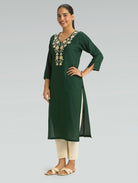 Woman wearing a green kurta with white embroidery on a gray background