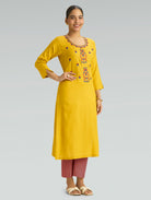 “A woman wearing a straight-fit yellow kurta with a round neckline and computerized thread embroidery, paired with pink pants, set against a gray background.”