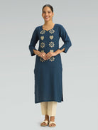 “A woman wearing a straight-fit blue kurta with a round neckline and computerized thread embroidery, set against a gray background.”