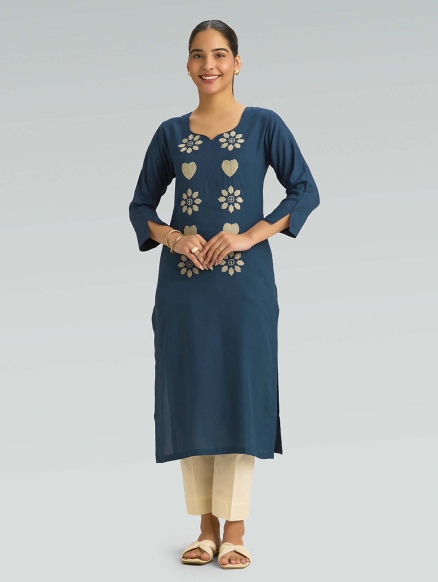 “A woman wearing a straight-fit blue kurta with a round neckline and computerized thread embroidery, set against a gray background.”