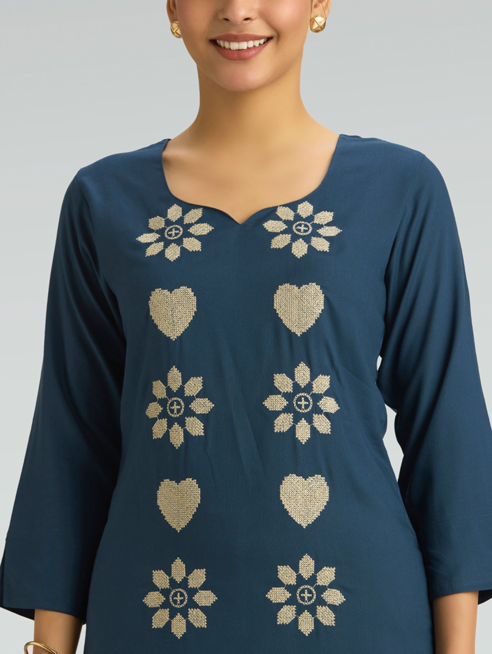 Woman wearing a blue kurta with white floral and heart patterns on a plain background