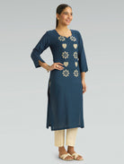 Woman wearing a blue kurta with floral patterns on a light gray background