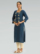 Woman wearing a blue kurta with floral patterns on a gray background