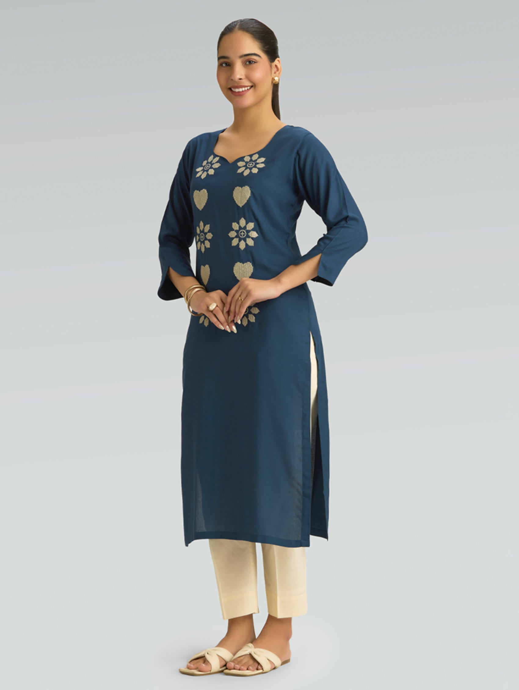 Woman wearing a blue kurta with floral patterns on a gray background