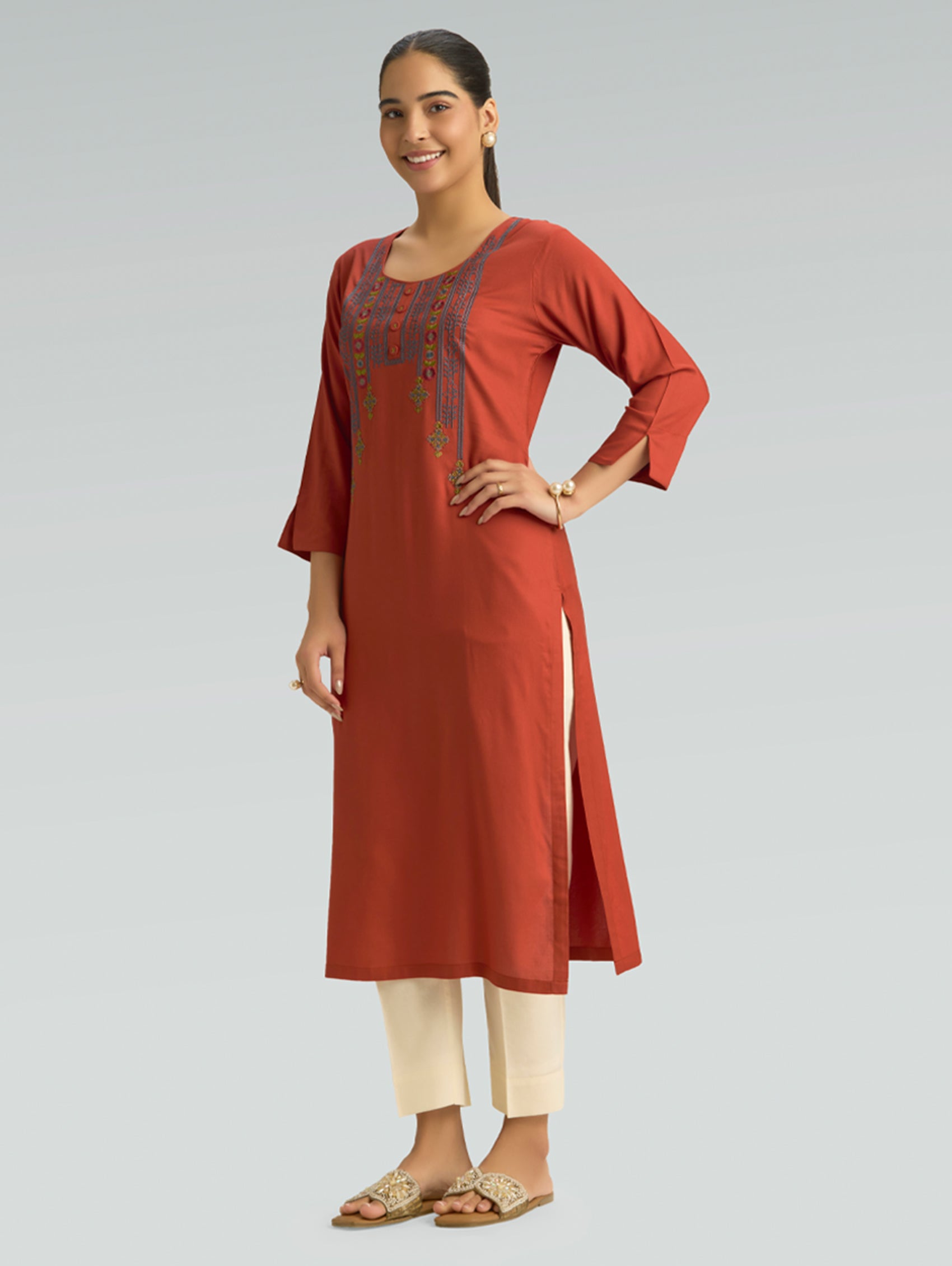 Woman wearing a red kurta with white pants on a light gray background