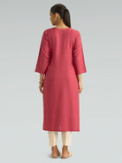 A woman in a straight-fit pink kurta with a round neckline, adorned with computerized thread embroidery, shown in a back pose against a soft gray background.
