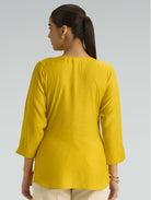 Woman wearing a mustard yellow kurta against a light gray background