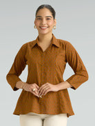 Woman wearing a brown patterned shirt against a gray background