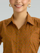 Woman wearing a mustard yellow floral shirt against a gray background