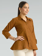 Woman wearing a brown patterned shirt against a gray background