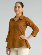 Woman wearing a brown patterned shirt against a gray background