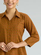 Woman wearing a brown patterned dress against a gray background