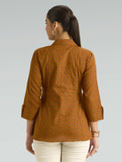 Woman wearing a brown patterned shirt on a gray background