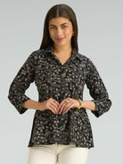 Woman wearing a black patterned shirt against a gray background