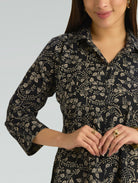 Woman wearing a black floral patterned shirt against a gray background