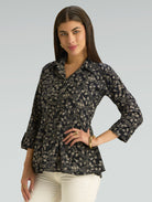 Woman wearing a black floral patterned blouse against a gray background