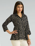 Woman wearing a black floral patterned shirt against a gray background