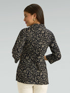 Woman wearing a black floral patterned shirt on a gray background