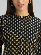 Black top with gold pattern worn by a model against a neutral background