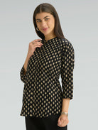 Woman wearing a black patterned top against a gray background
