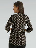 Woman wearing a black and beige patterned shirt against a gray background
