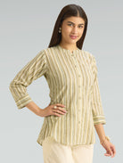 Woman wearing a green and white striped shirt against a gray background