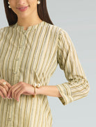 Woman wearing a green and beige striped dress with a plain background