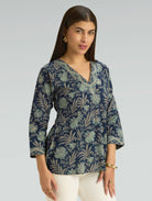 Woman wearing a blue floral patterned top against a gray background