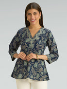 Woman wearing a blue floral patterned blouse against a gray background