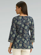 Woman wearing a navy floral patterned top against a gray background