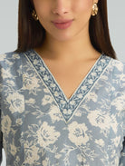Woman wearing a blue floral patterned top with a neutral background