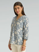 Woman wearing a blue floral blouse against a gray background