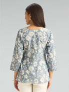 Woman wearing a floral blouse with a gray background