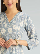 Woman wearing a light blue floral patterned kurta on a gray background