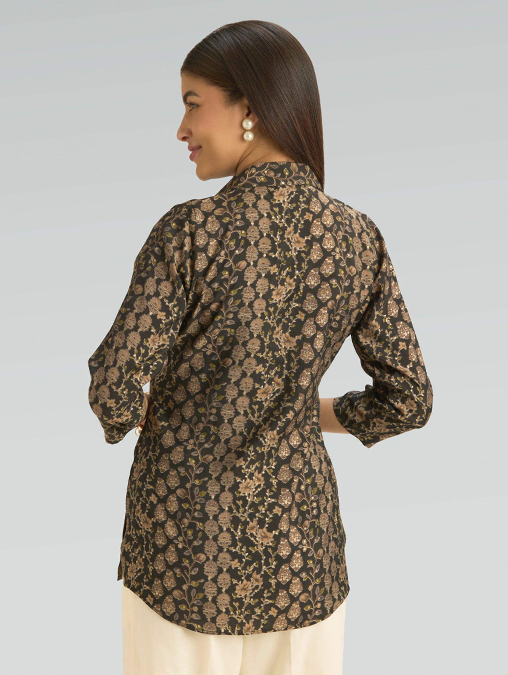 Woman wearing a patterned shirt with long sleeves on a gray background