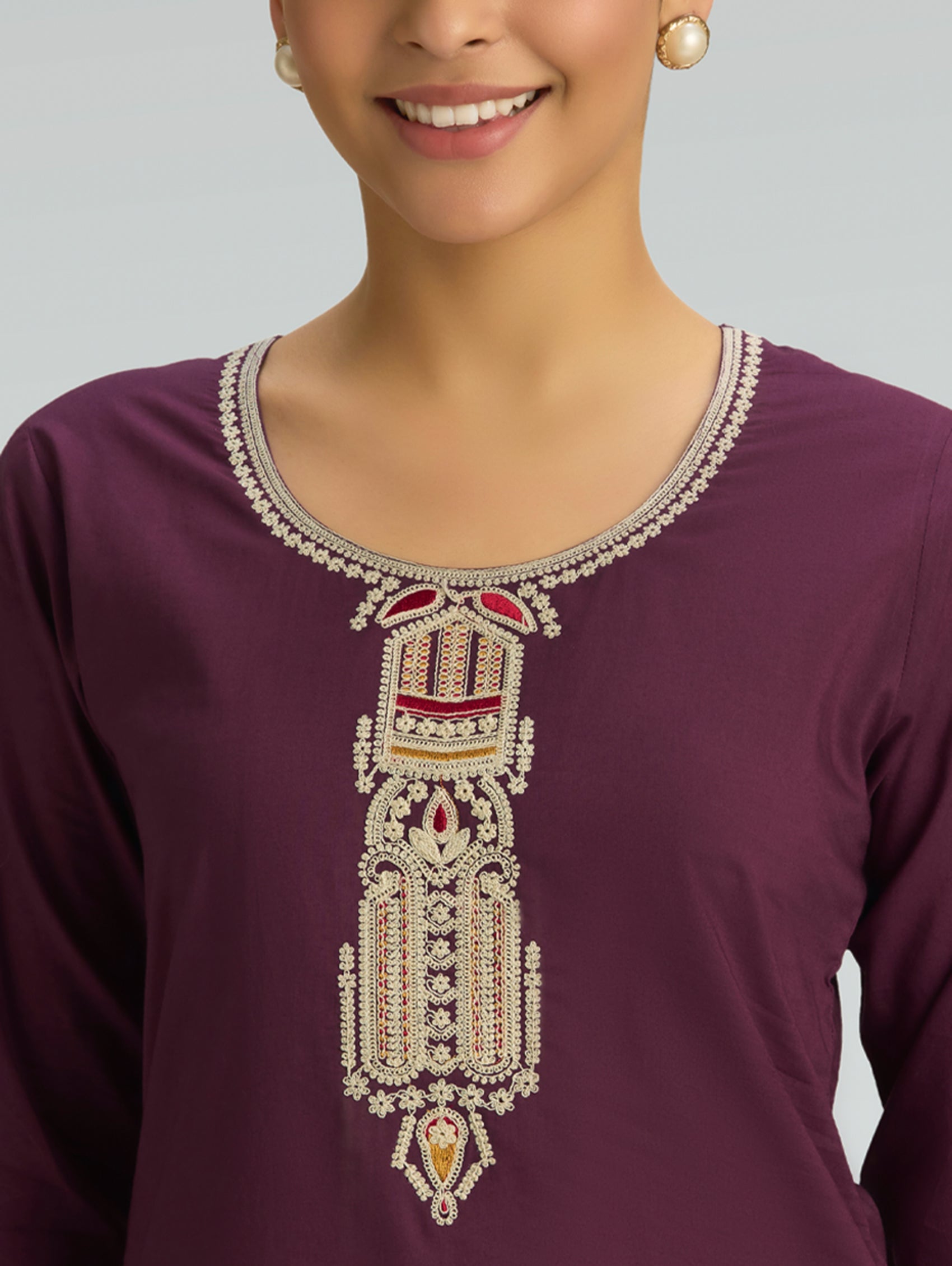 Purple top with intricate white embroidery on a plain background