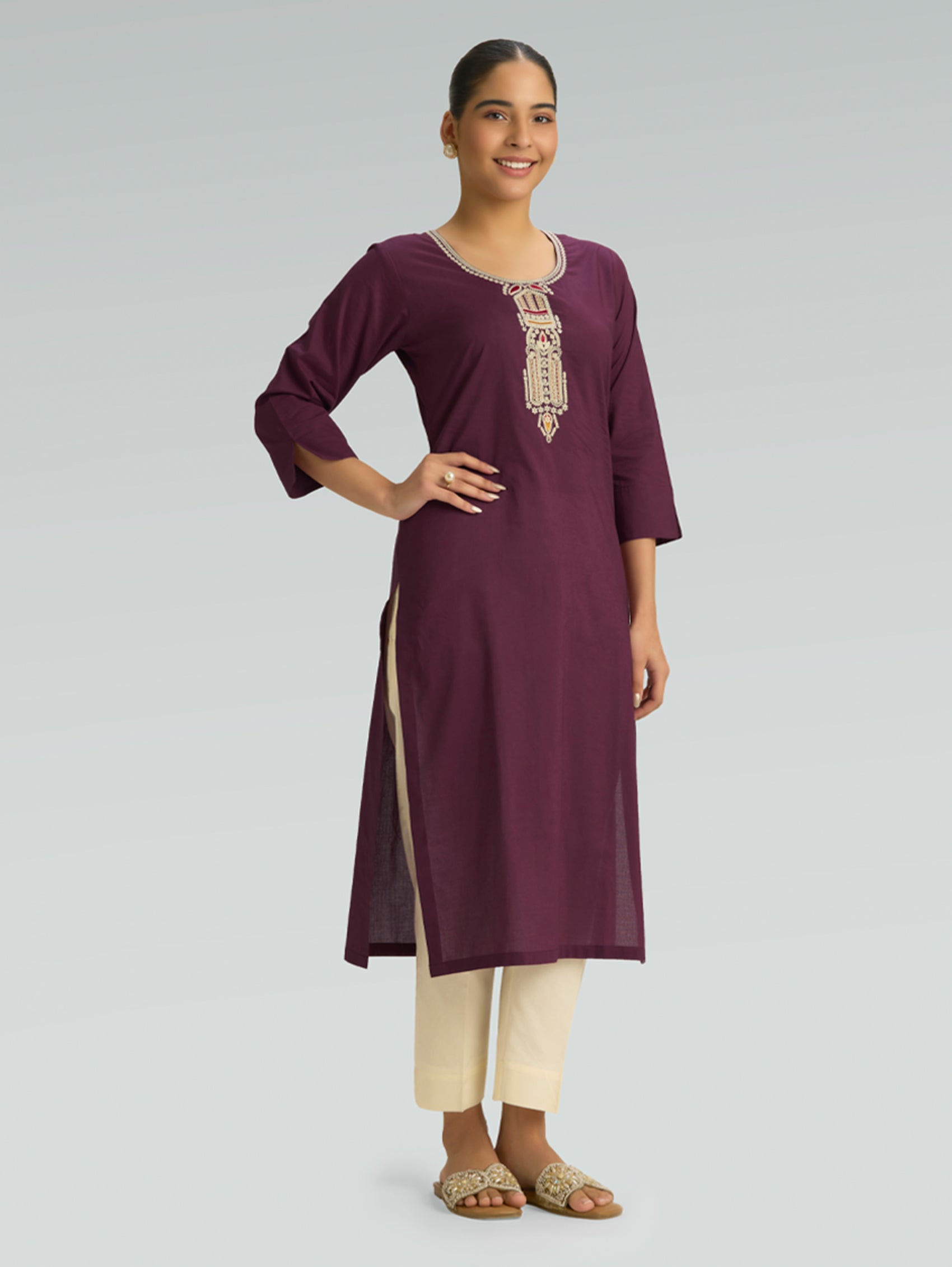 Woman wearing a maroon kurta with white embroidery on a gray background