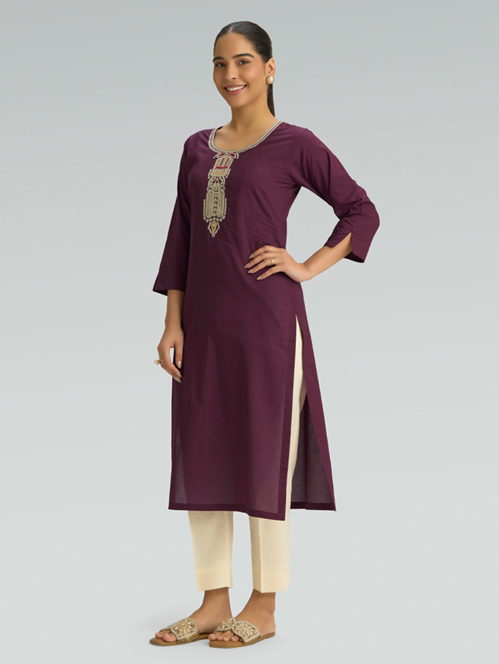 Woman wearing a purple kurta with white pants on a gray background