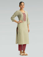 A woman wearing a straight-fit beige kurta with a round neckline, adorned with red embroidery, set against a light gray background.