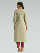 A woman in a beige kurta paired with maroon pants, shown in a back pose against a light gray background.
