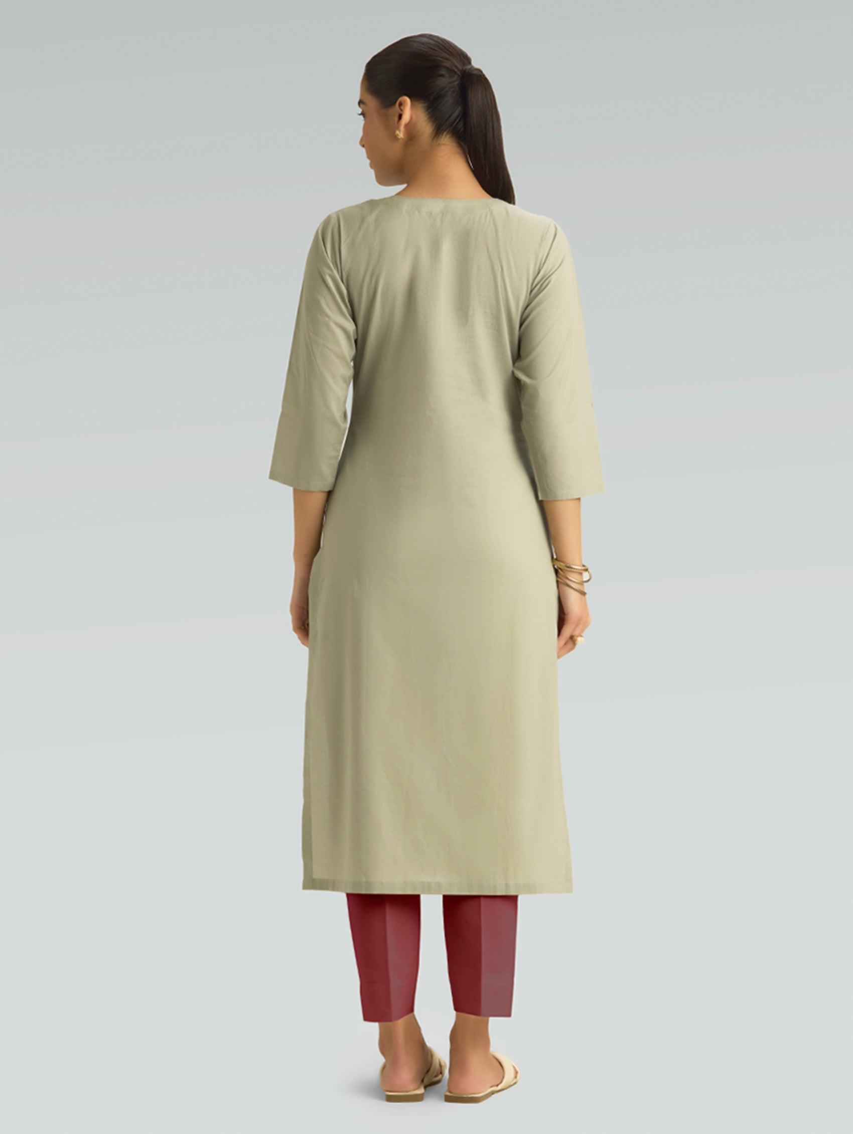 A woman in a beige kurta paired with maroon pants, shown in a back pose against a light gray background.