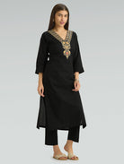 Woman in a straight-fit black kurta with a V-neck and computerized thread embroidery on a light gray background.
