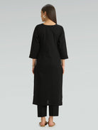 Back view of a woman in a black kurta, elegantly set against a clean, plain background.
