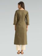 Woman wearing a green kurta with white pants on a gray background