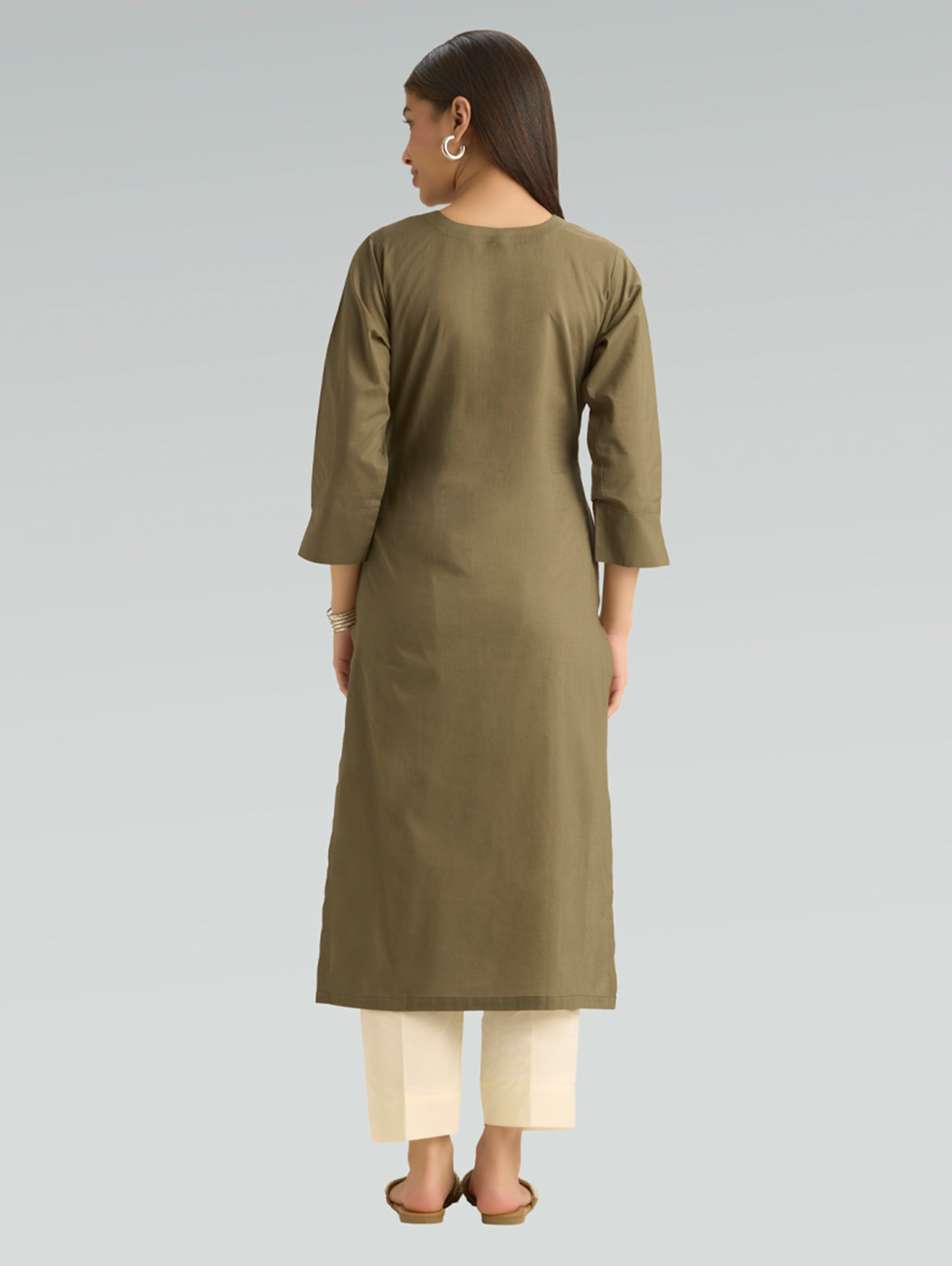 Woman wearing a green kurta with white pants on a gray background